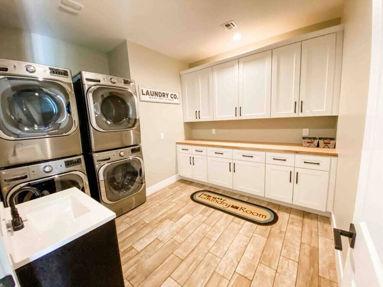 A laundry room with stacked washers and dryers, a sink, and a sign that reads 'Laundry Co.'