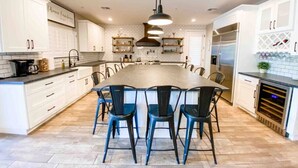 A modern kitchen with a central island, white cabinetry, and a built-in oven.