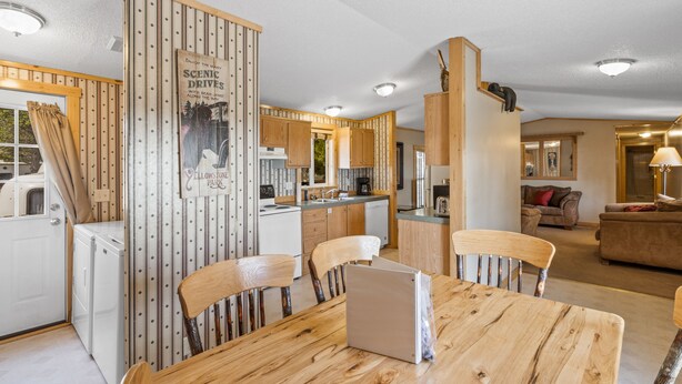 Une cuisine moderne avec des meubles en bois, une table à manger avec des chaises et un réfrigérateur.