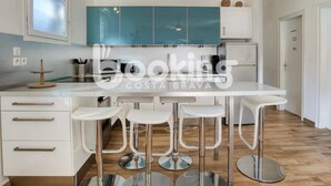 A modern kitchen with a white countertop, four bar stools, and teal cabinets. - APARTMENT FOR 6 PEOPLE WITH PARKING 2 MINUTES FROM THE BEACH (Platja d'Aro)