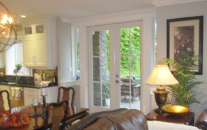 A dining area with a table set for two, a leather sofa, a lamp, and a potted plant.