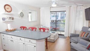 Une cuisine moderne avec des meubles blancs, un plan de travail gris et un coin repas avec des chaises rouges.