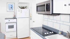 Une cuisine compacte équipée d’un four à micro-ondes, d’un four traditionnel et d’une plaque de cuisson intégrée.