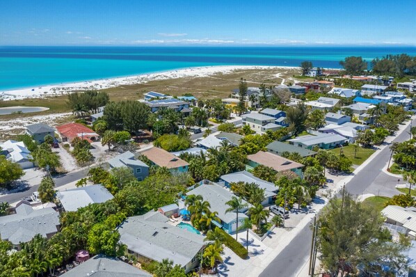A coastal residential area with houses, a beach, and clear blue waters.