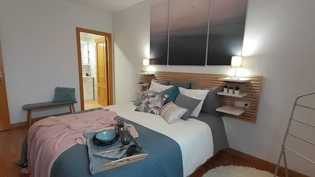 Um quarto com cama, mesas de cabeceira, escrivaninha, cadeira e guarda-roupa.