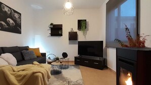 Uma sala de estar moderna com sofá, televisão, lareira e obras de arte na parede.