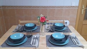 Uma mesa de jantar posta com pratos azuis, copos e talheres, com um vaso de flores no centro.