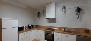A compact kitchen with white cabinets, a built-in oven, a microwave, and a sink.