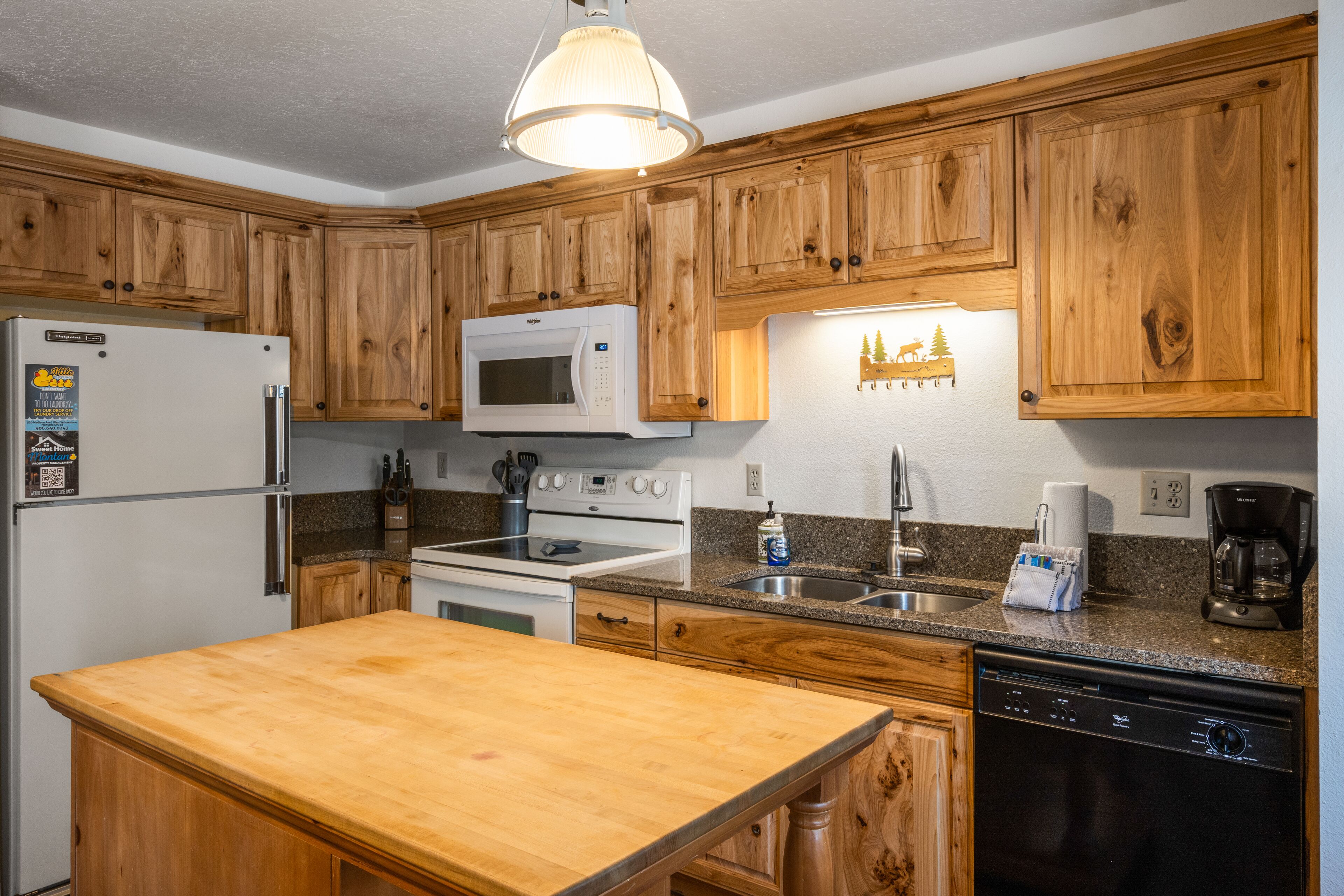 A kitchen with wooden cabinets, a refrigerator, a microwave, a stove, a sink, and a dishwasher.