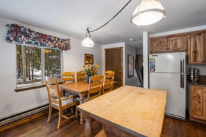 Una cocina con armarios de madera, un refrigerador y una mesa de comedor con sillas.