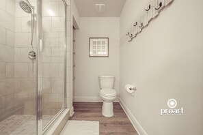 Ein Badezimmer mit einer Duschkabine, einer weißen Toilette und einem gerahmten Bild an der Wand.