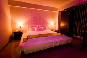 A bedroom with a large bed, two bedside tables, a nightstand, and a wardrobe. - Joneya Hotel (Chiclayo)