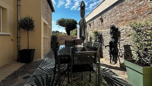 An outdoor patio with a table and chairs, a patterned rug, and potted plants. - Le Biardais - Gites du Bessin (Balleroy-sur-Drôme)