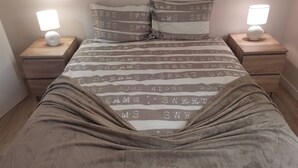 A neatly made bed with a striped bedspread and matching pillows, flanked by two bedside tables with lamps. - 2 bedroom apartment Sao Giao 10A in Tomar (Tomar)