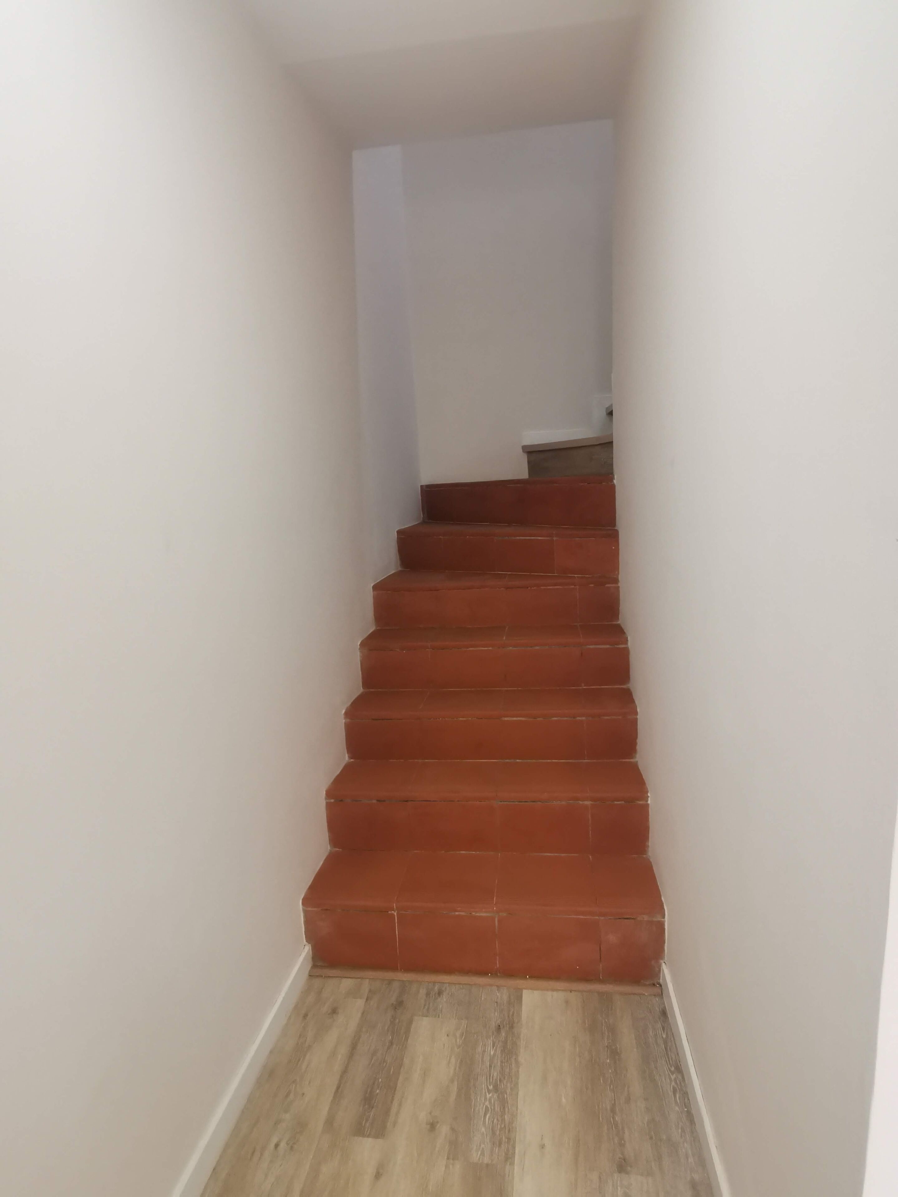 Un escalier aux marches rouges menant à un palier.