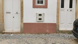 A building with two white doors, a window with bars, and a utility box. - 2 bedroom apartment Sao Giao 10A in Tomar (Tomar)