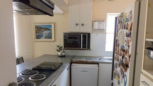 A compact kitchen with a gas stove, microwave, and refrigerator.
