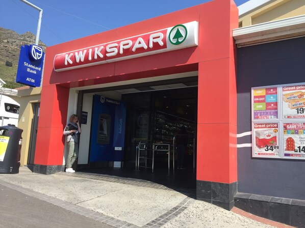 A Kwik-Spar store with a red facade, a Standard Bank ATM, and a sign advertising a 75% discount on crystal glass.