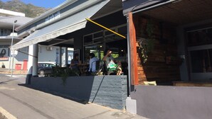 A café with outdoor seating, a visible entrance, and a mountain in the background.