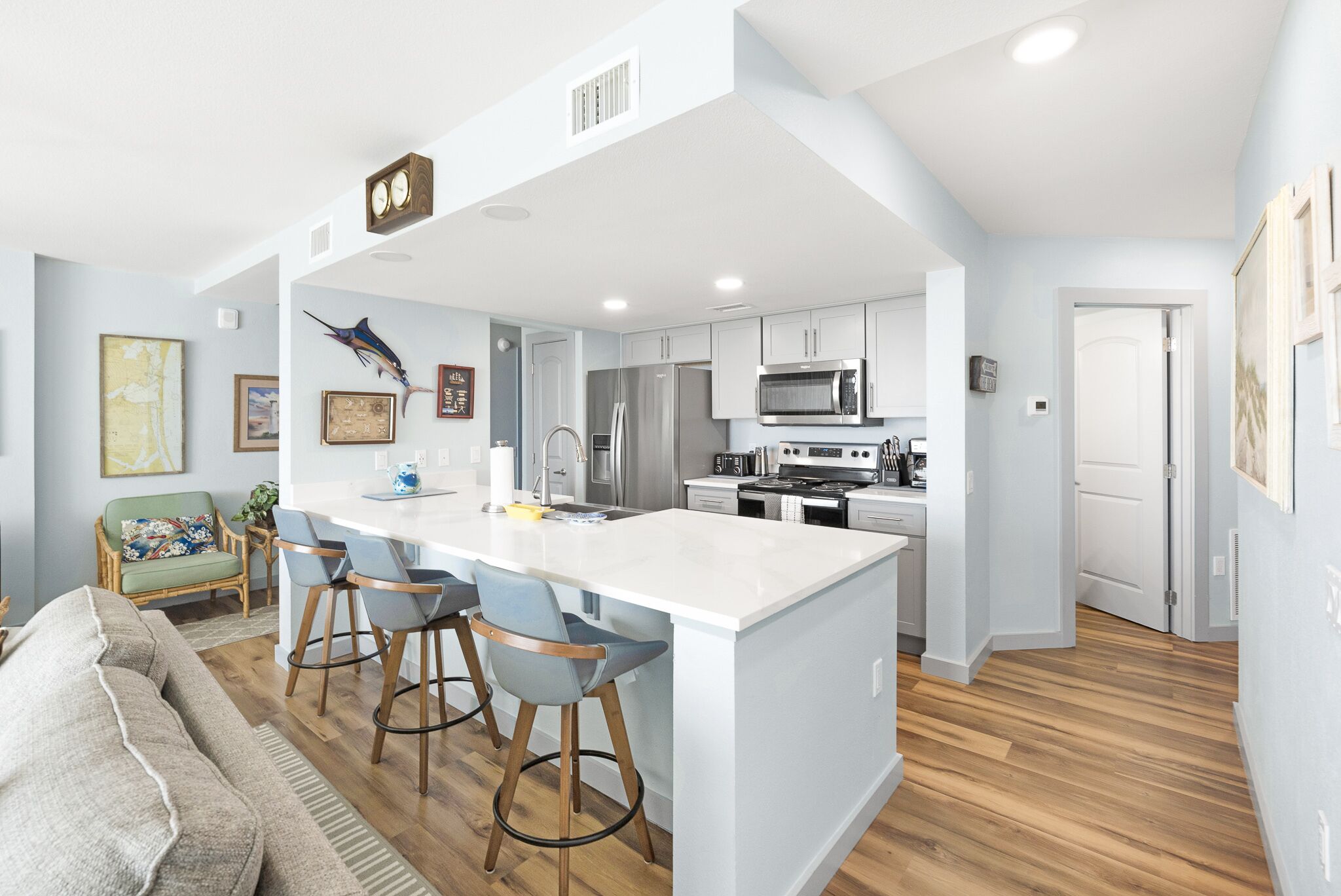 A modern kitchen with a central island, bar stools, and stainless steel appliances.