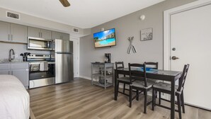 A modern kitchen with stainless steel appliances, a dining area with a table and chairs, and a ceiling fan. - Sandcastle Condominiums Unit 207  (Port Aransas)