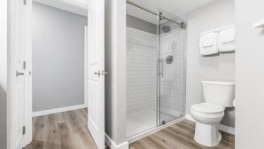 A bathroom with a glass-enclosed shower, a toilet, and a towel rack. - Sandcastle Condominiums Unit 207  (Port Aransas)