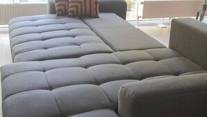 A modern living room with a large sectional sofa and a small table. - New York style, parking lot, lockable bike box with charging facility  (Koblenz)