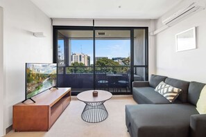 A modern living room with a sofa, a coffee table, and a TV on a wooden stand.
