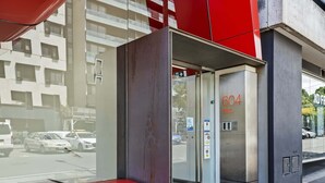 Ein Aufzug mit der Nummer 604, einer Glastür und einer roten Bank davor.