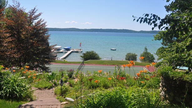 A lakeside view with boats docked, a pathway, and surrounding greenery.