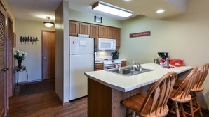 A compact kitchen with wooden cabinets, a refrigerator, a microwave, and a sink. - Westcreek Ranch - No Stairs! (Branson West)