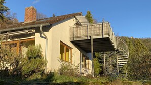 Uma casa com varanda, chaminé e parede de pedra.