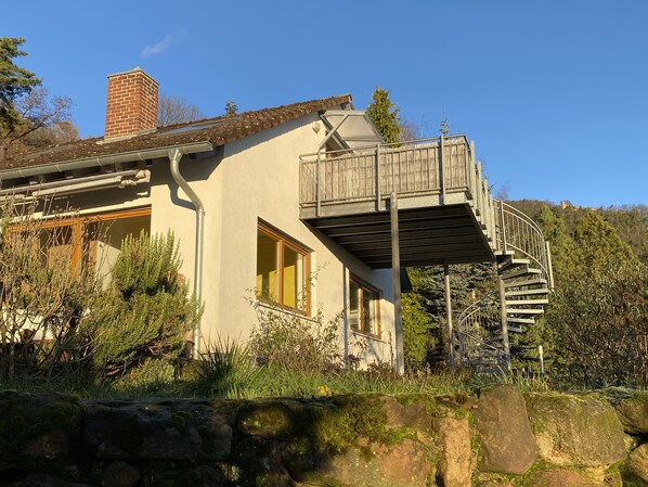 A house with a balcony, a chimney, and a stone wall.