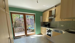 A kitchen with a sliding glass door leading to a patio area, a stove, and a coffee maker.