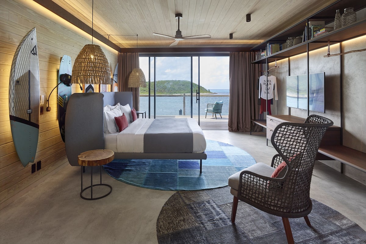 Un dormitorio moderno con una cama grande, un espacio para sentarse y vistas al mar.