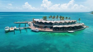 A tropical island resort with multiple overwater bungalows connected by walkways, a dock with boats, and clear turquoise waters. - Saba Rock Resort (Saba Rock)
