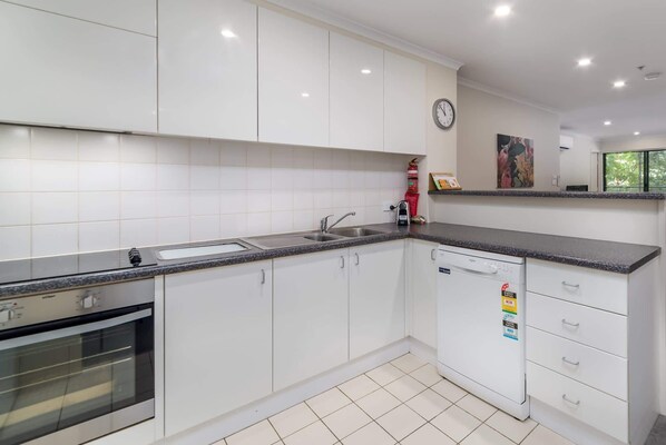 A modern kitchen with white cabinets, a stainless steel sink, and a dishwasher.