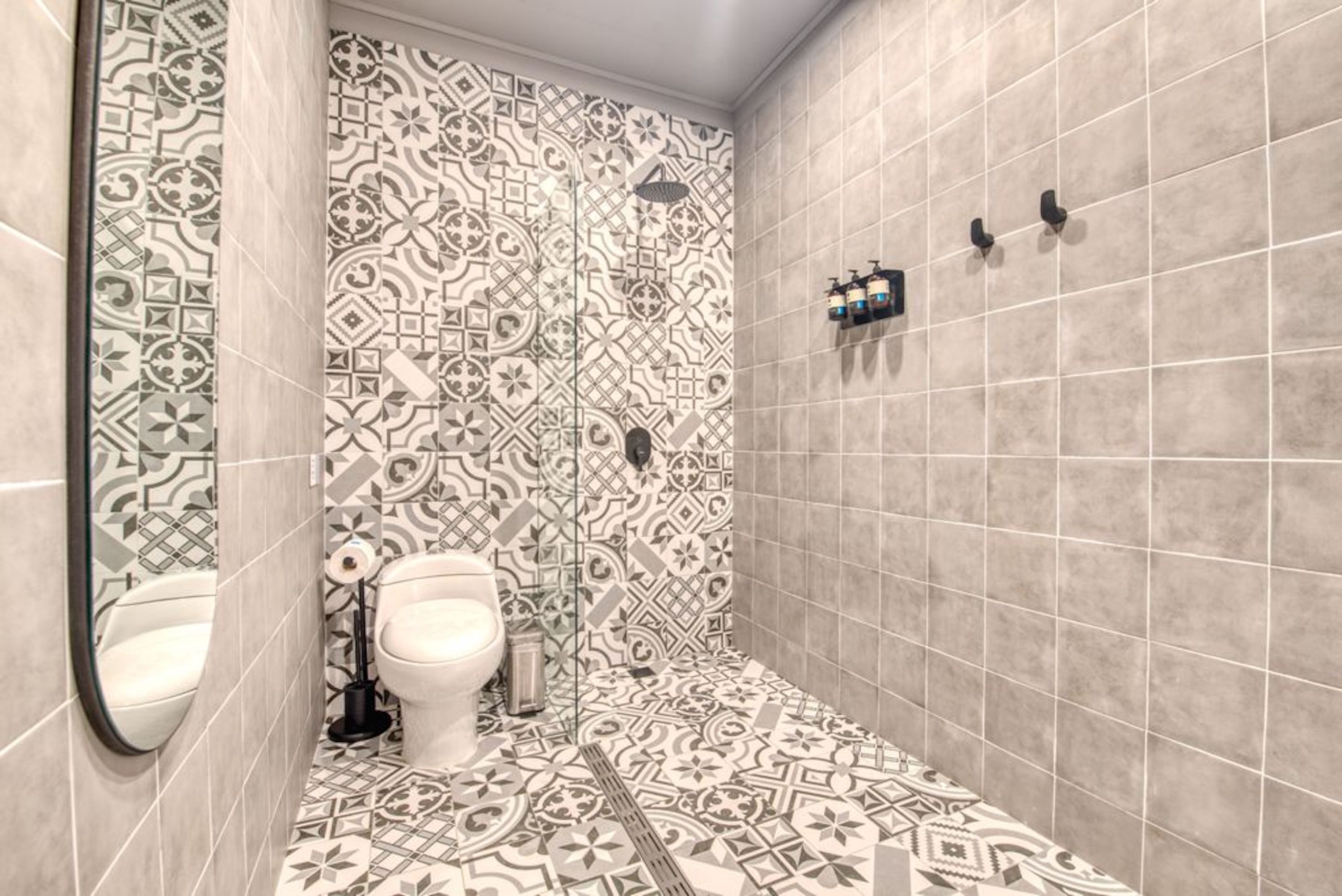 A bathroom with patterned tiles, a toilet, a bidet, and a shower area.