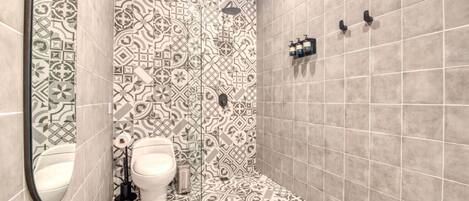 A bathroom with patterned tiles, a toilet, a bidet, and a shower area.