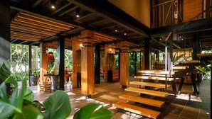 A spacious indoor area with wooden beams, large windows, and a variety of seating arrangements. - awā Beachfront Hotel (Cahuita)