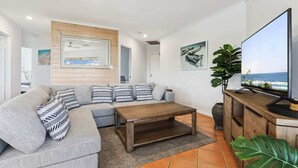 Ein modernes Wohnzimmer mit Sofa, Couchtisch und Fernseher.