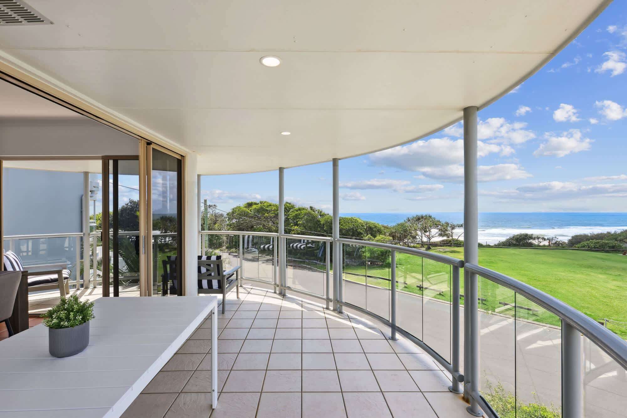 Een balkon met uitzicht op de oceaan en een gazon.