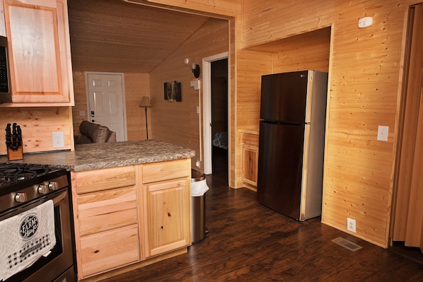 A kitchen with wooden cabinets, a stainless steel refrigerator, a granite countertop, and a stove.