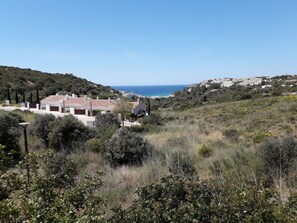 Uma propriedade costeira com vista para o mar, rodeada por vegetação e colinas.