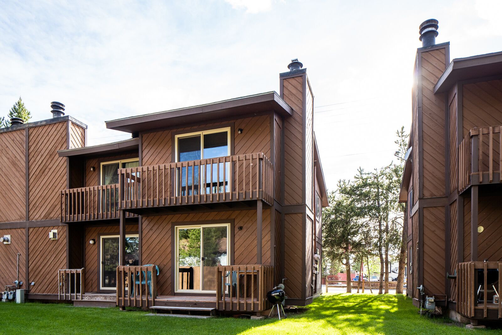 A modern multi-story building with wooden exterior, balconies, and a well-maintained lawn.