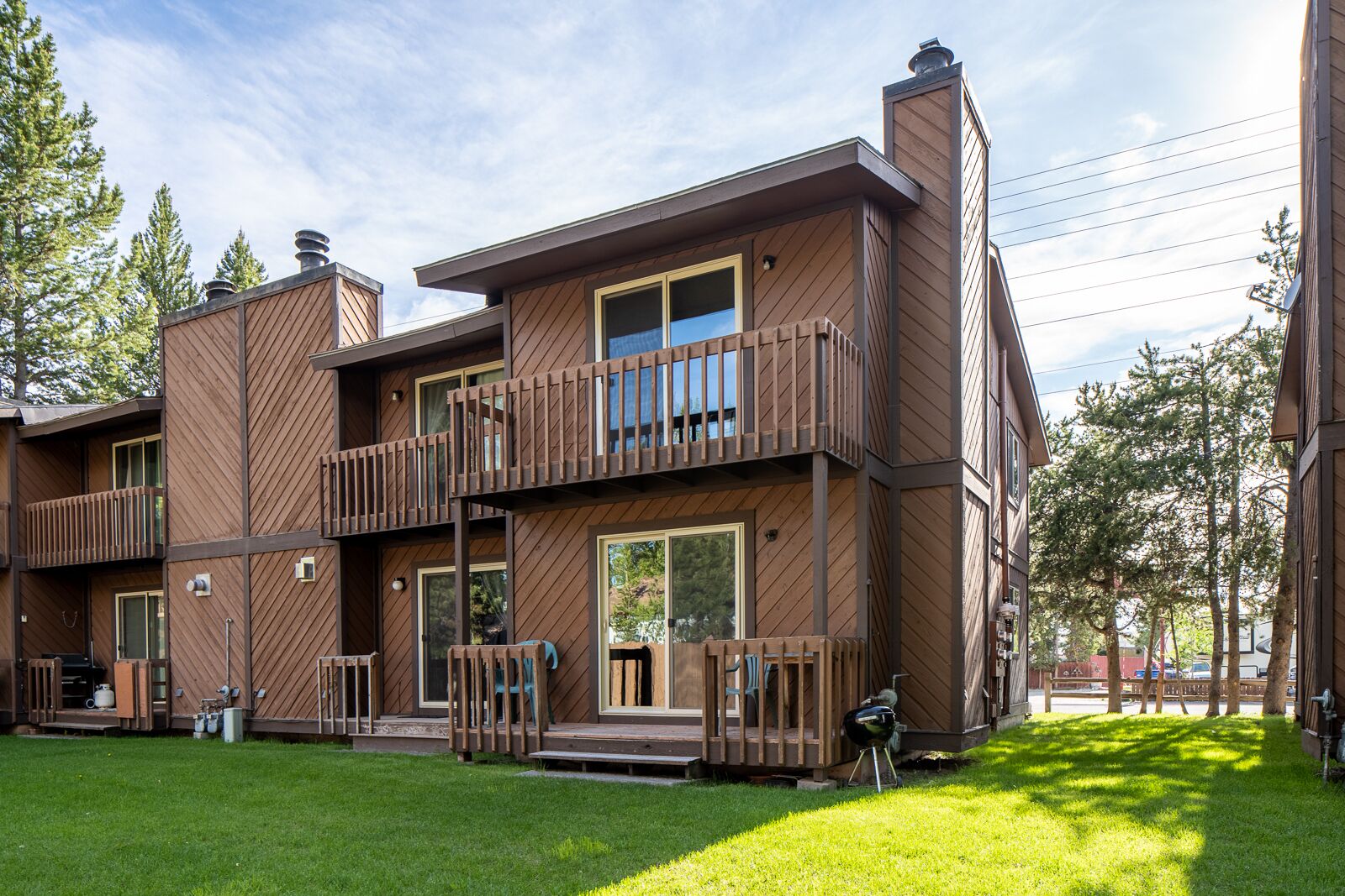 Un immeuble en bois à plusieurs étages, doté de balcons, de grandes fenêtres et d’une pelouse bien entretenue.