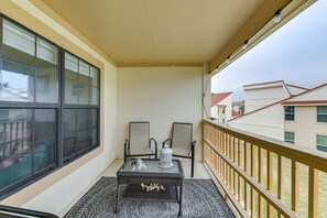 Relax on the balcony with a view, featuring a glass door, two chairs, and a small table.