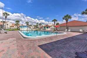 Relax by the rectangular pool surrounded by palm trees and lounge chairs.