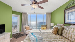 A hotel room with a bed, a chair, a television, and a view of the ocean. - Gulf Front Living Room AND Master Suite! Sleeps 8! (Panama City Beach)