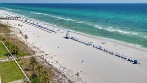 A beach with a long row of blue umbrellas and lounge chairs along the shoreline. - Gulf Front Living Room AND Master Suite! Sleeps 8! (Panama City Beach)